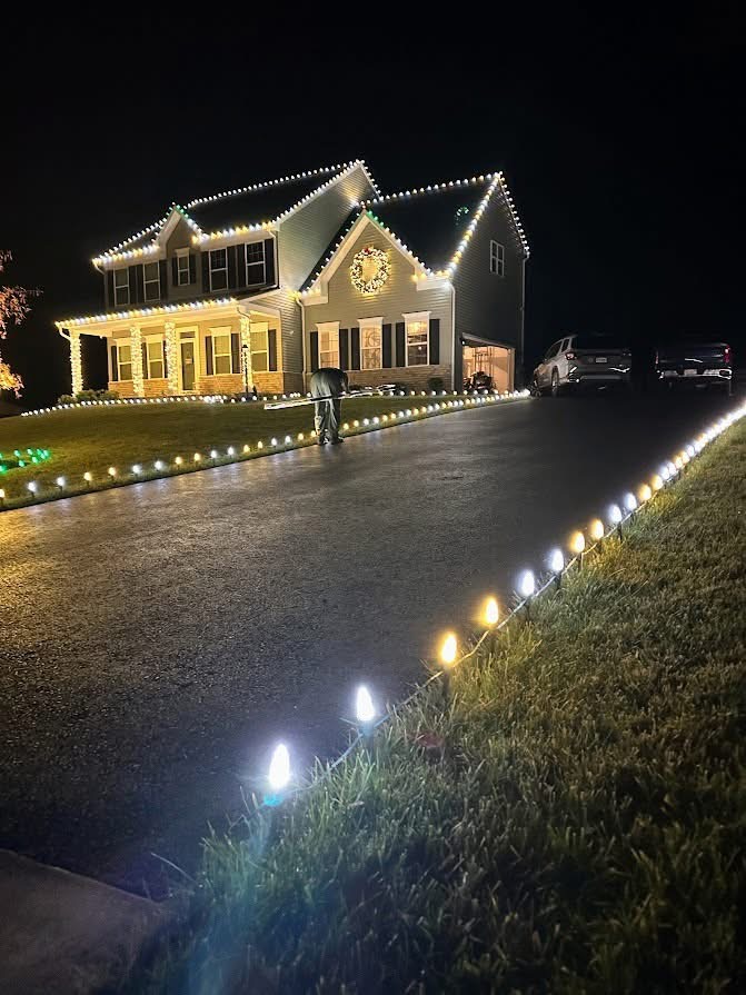 Home with warm white lights and a driveway lined in glowing pathway lights during installation