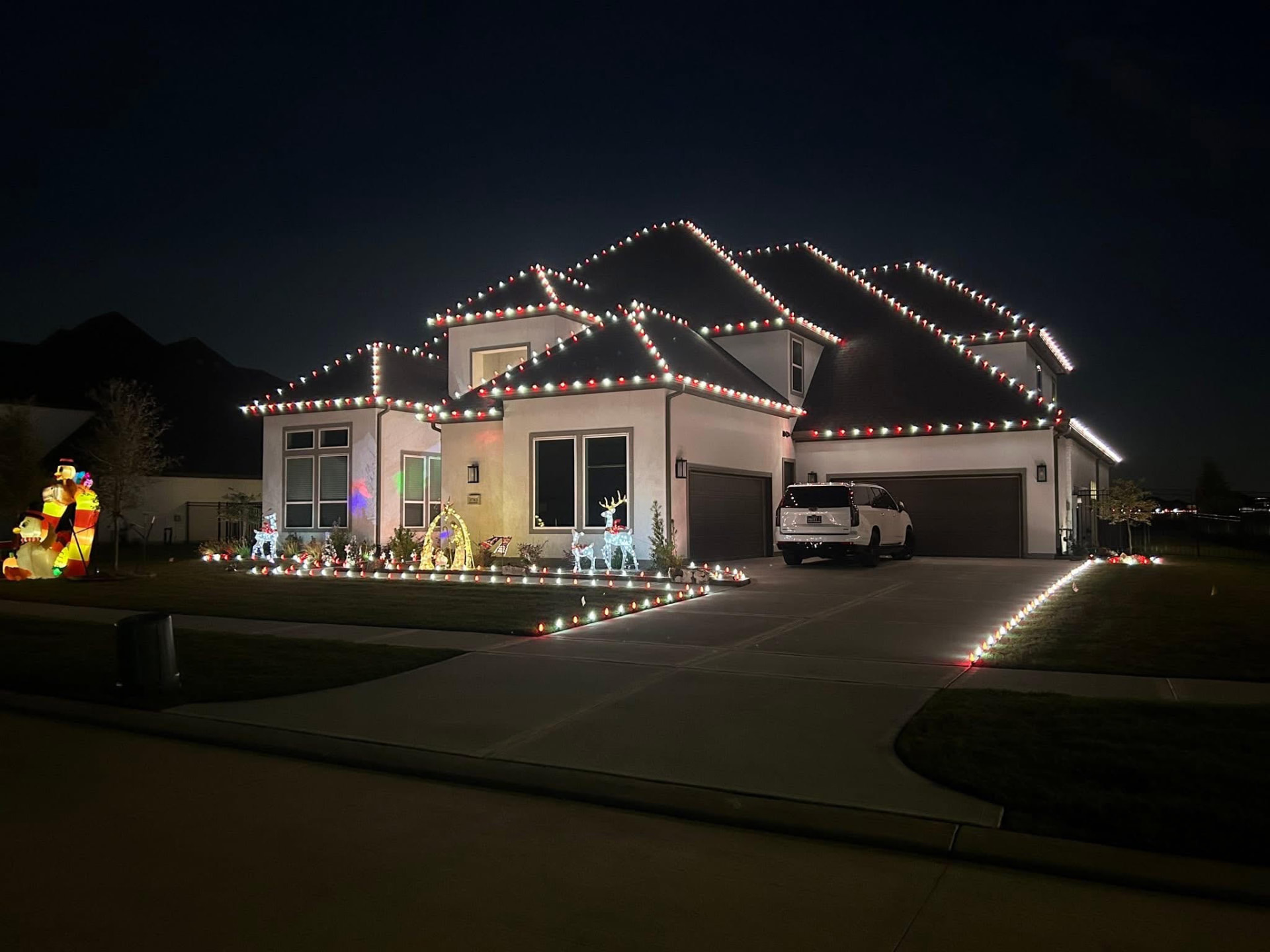 St. Louis area home decorated with red and white Christmas roofline lights, lit reindeer, and yard displays by Midwest Elves