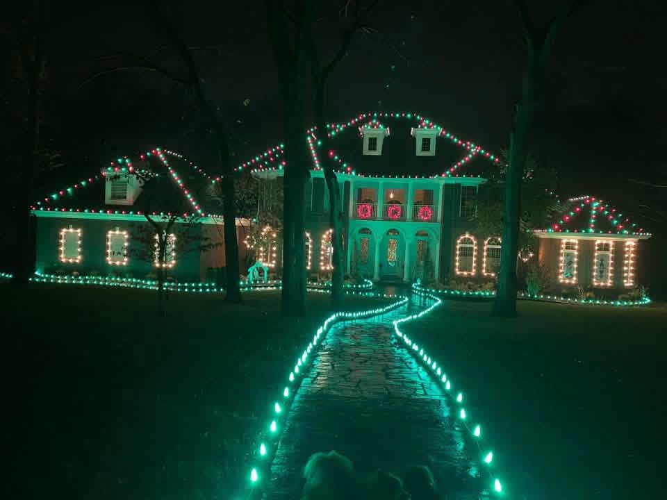 Home with red, green, and warm white Christmas lights and a glowing green walkway