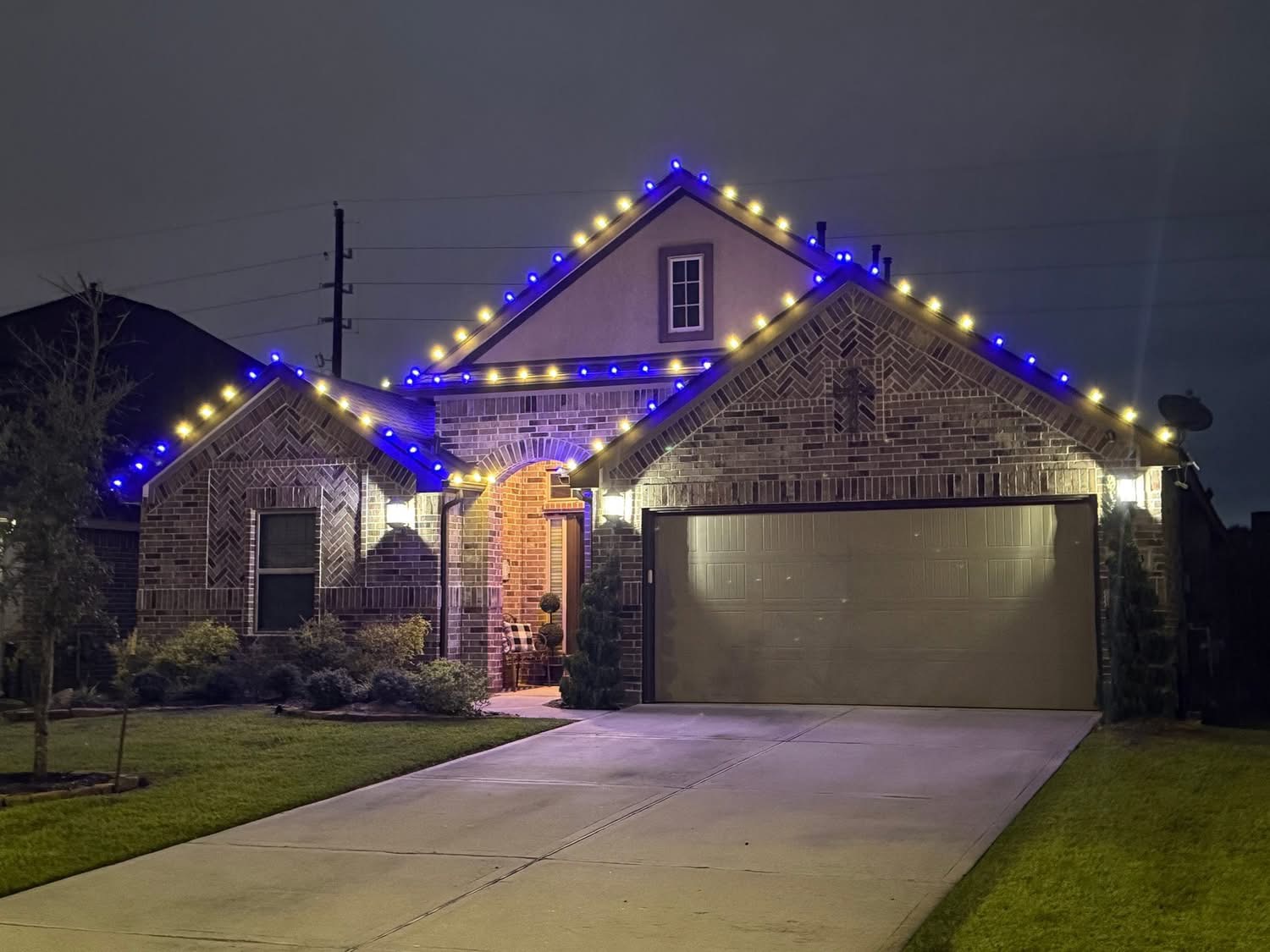Brick home with alternating blue and warm white Christmas lights along the roofline