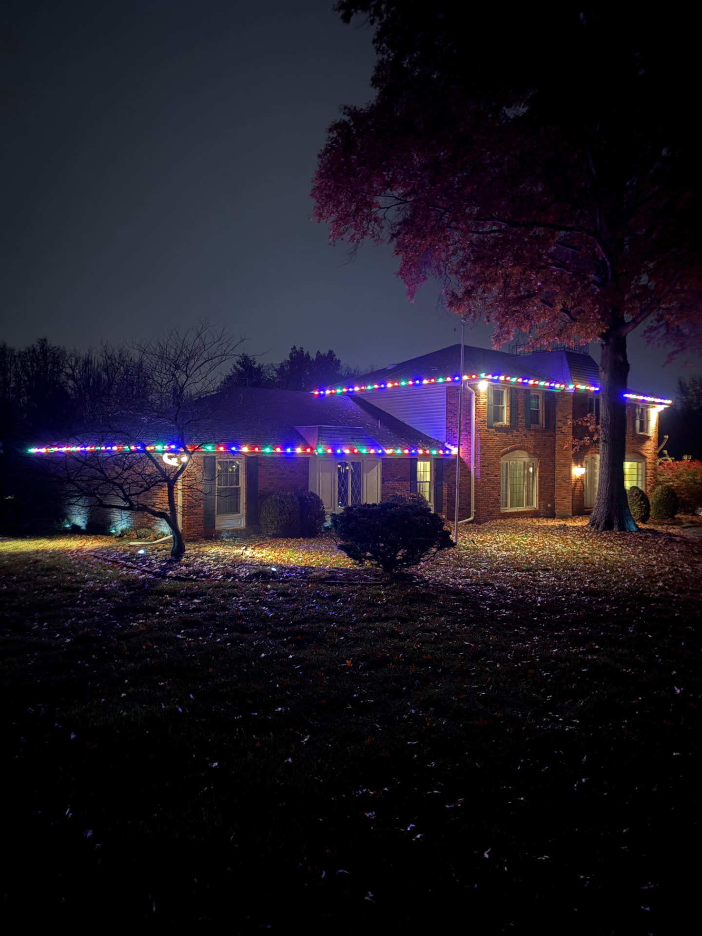 Brick home decorated with classic multicolor Christmas roofline lights